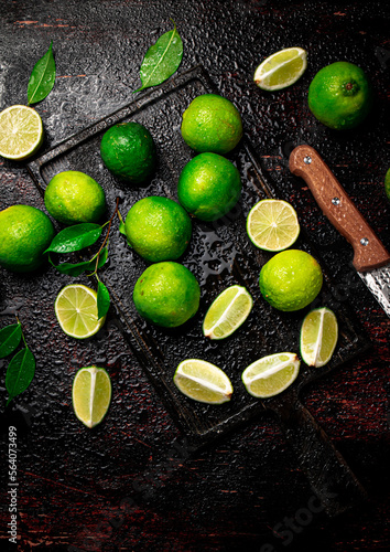 Sliced lime with leaves on a cutting board with a knife.