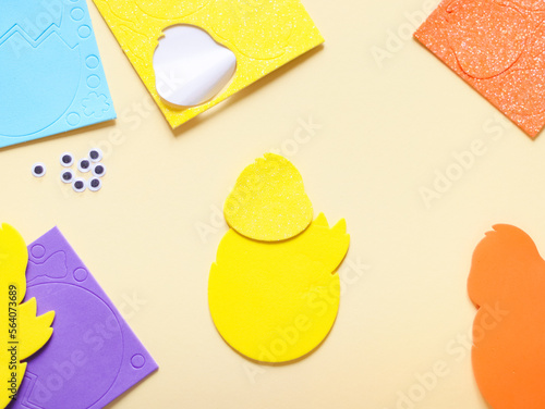 Colored felt set of yellow chicken and patterned stickers lying on the sides on a pale yellow