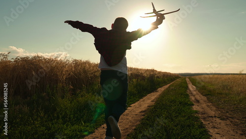 Happy teen boy plays with toy plane on field, sunset. Boy wants to become pilot astronaut. Slow motion. Silhouette, Teenager dreams of flying, becoming pilot Airplane. Children play with toy airplane photo