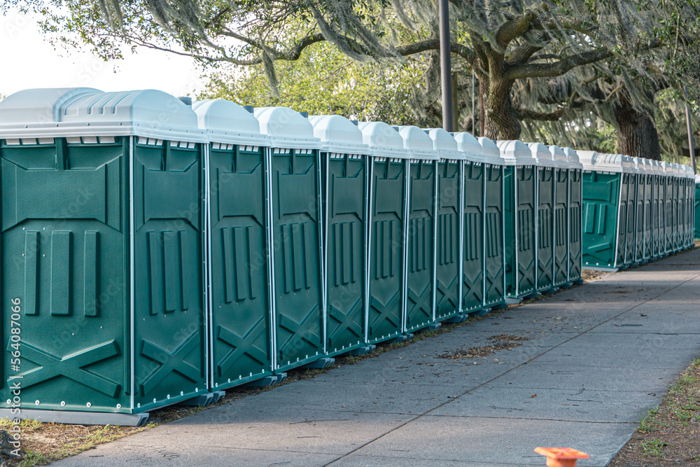 Row of green porta portable potty outhouses ready for use at a concert, festival, or event Row of green porta portable potty outhouses ready for use at a concert, festival, or event