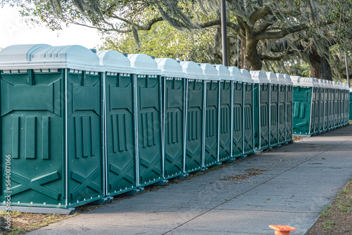 Row of green porta portable potty outhouses ready for use at a concert, festival, or event photo