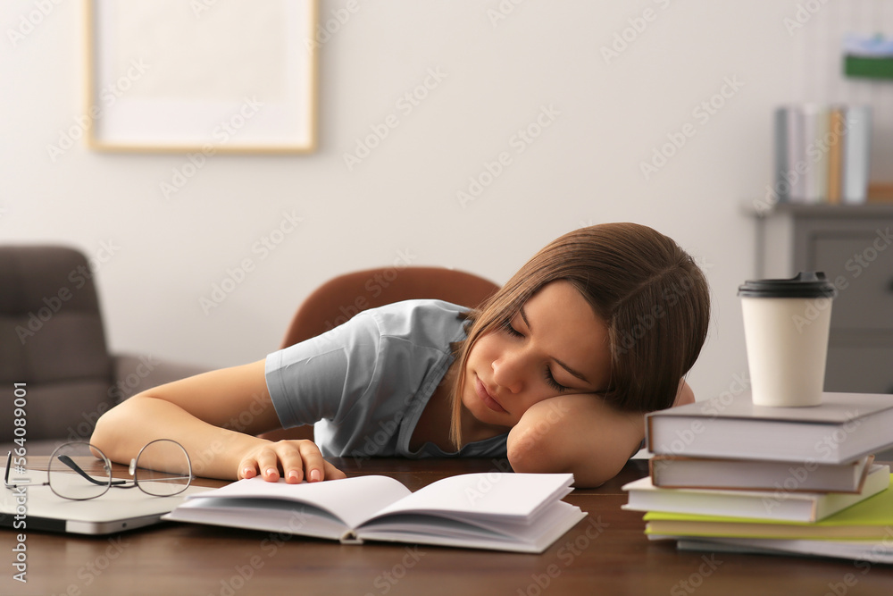 Young tired woman sleeping near books at wooden table indoors Young tired woman sleeping near books at wooden table indoors