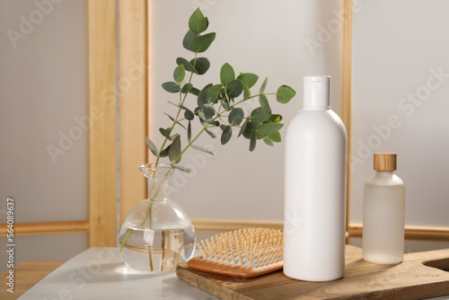 Bottles of shampoo and hairbrush on white table