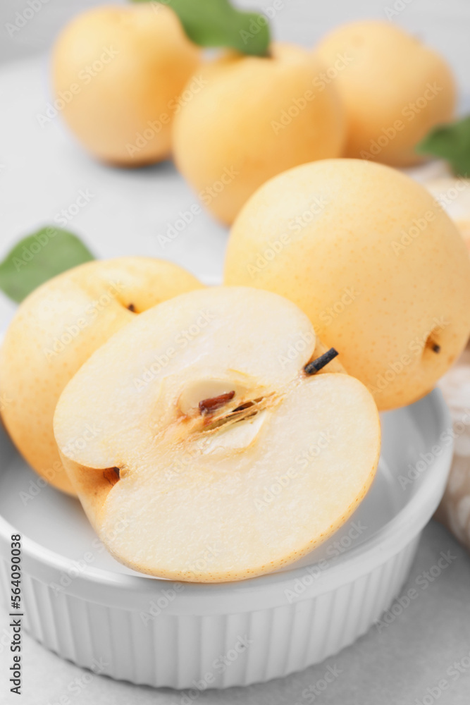 Bowl with delicious apple pears on white table, closeup