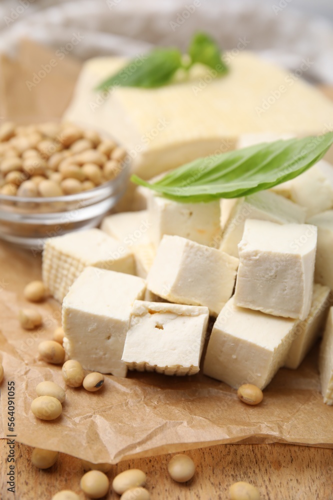 Delicious tofu cheese, basil and soybeans on wooden board, closeup