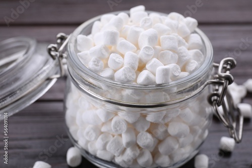 Glass jar with delicious marshmallows on wooden table, closeup