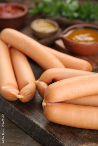 Many fresh delicious sausages on wooden table, closeup