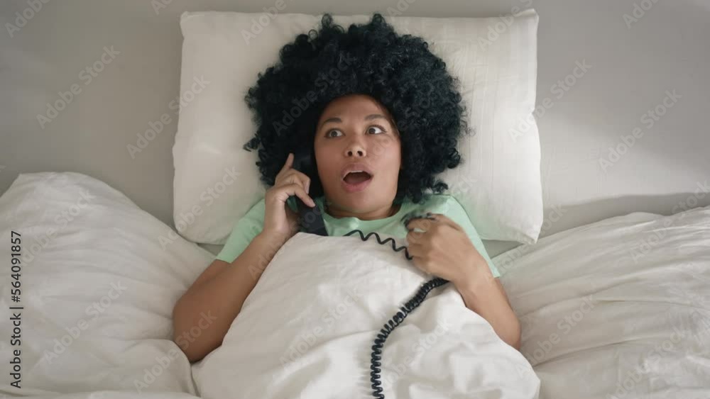 Indoor shot Portrait of dark haired curly woman in mint cotton pajama lying in kind size comfortable bed with handset phone talking with girlfriend discussing current gossips or relationships rumors Indoor shot Portrait of dark haired curly woman in mint cotton pajama lying in kind size comfortable bed with handset phone talking with girlfriend discussing current gossips or relationships rumors