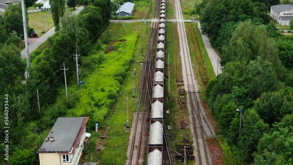 Railway cargo train wagon rides on railroad. Transportation and delivery of cargo in containers. Aerial view over train riding near river and coal power plant. Railway cargo train wagon rides on railroad. Transportation and delivery of cargo in containers. Aerial view over train riding near river and coal power plant.