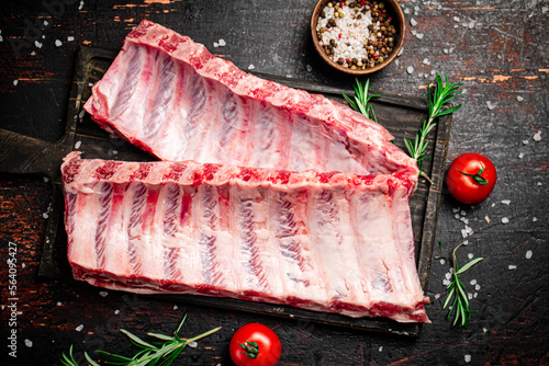 Raw ribs with spices and tomatoes on the table. 