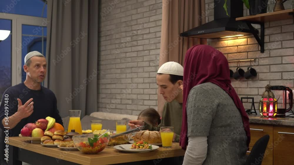 Happy Muslim parents having evening meal with their kids at dining table at home. People Break the Ramadan Fast Happy Muslim parents having evening meal with their kids at dining table at home. People Break the Ramadan Fast