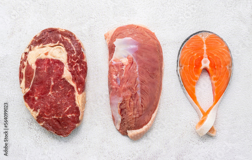 Steak concept with salmon  steak, rib eye steak and duck breast set up on white concrete background.