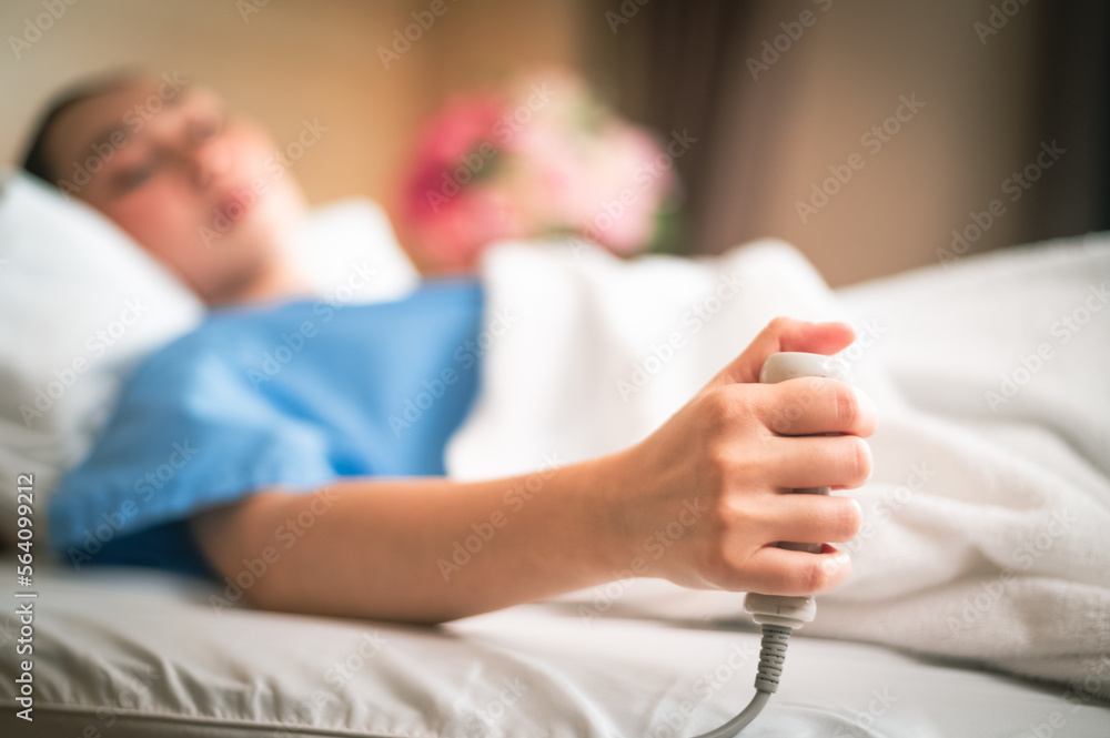 Patient in a hospital room calling a nurse. A hand holding press emergency button in hospital room. Emergency button for hospital patients.