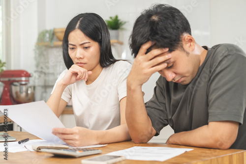 Stressed, hand of asian young couple love family, confused by calculate expense from invoice or bill, have no money to pay. Mortgage, loan causing debt, bankruptcy. Debt problems, Financial people. © KMPZZZ