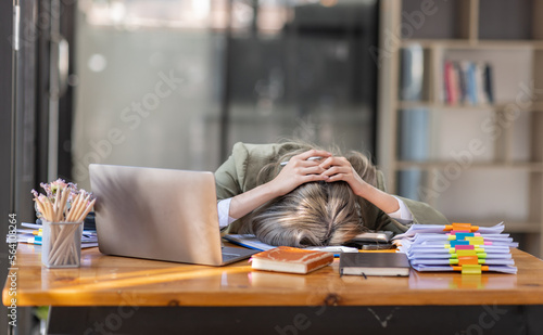 Bored Young business Asian woman sitting at her workplace at the office esk for a long time, Work mental health feel boring and Lazy, Freelance employees sleeping lying, Stress concept. photo