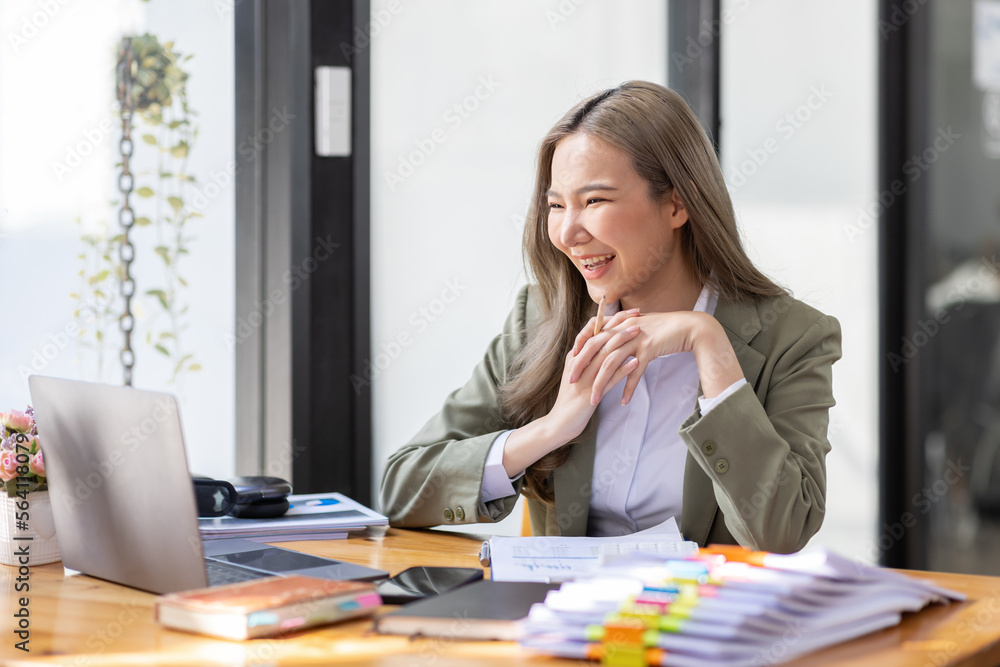 Everyday winner Excited Asian woman raising her arms while sitting at the desk in office, Happy excited employees work or business successful concept. Everyday winner Excited Asian woman raising her arms while sitting at the desk in office, Happy excited employees work or business successful concept.