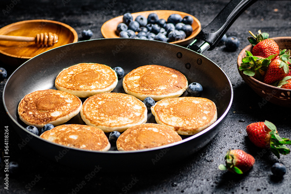 Pancakes in a frying pan with fresh berries and honey. Pancakes in a frying pan with fresh berries and honey.