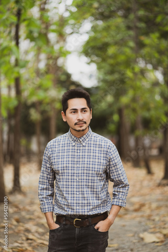 Man with beard and plaid shirt of aesthetic lumberjack in the middle of nature in portrait looking out.