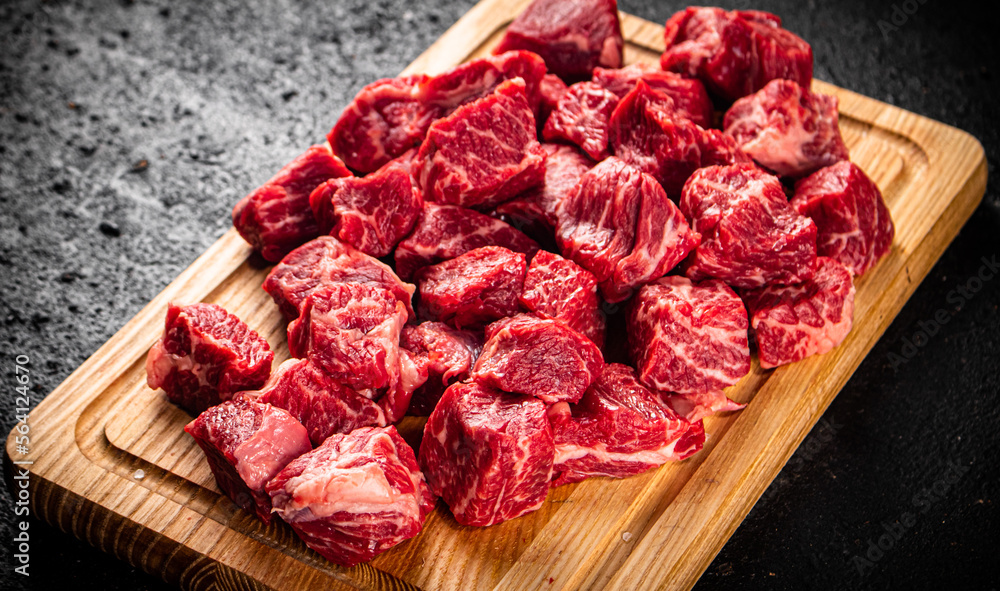 Raw pieces of beef on a wooden cutting board. Raw pieces of beef on a wooden cutting board.