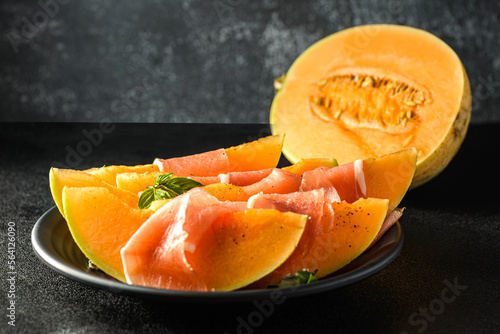 melon with parma on a dark background