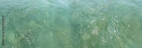 Wide banner for a web site. Sea water close-up, surface view from above. Sand bottom is visible through the water column. Clean ocean, ecology, environment. Background with space for inscription. 