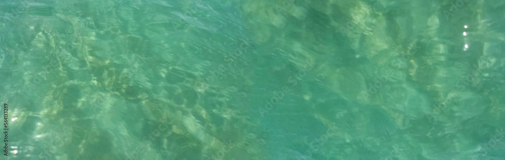 Beautiful bright turquoise sea water close up. Slight ripples and glare from the sun's rays reflecting from the water surface. Top view. Clear transparent ocean. Panorama. Open borders frame. Idea 