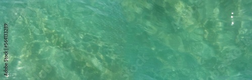 Beautiful bright turquoise sea water close up. Slight ripples and glare from the sun's rays reflecting from the water surface. Top view. Clear transparent ocean. Panorama. Open borders frame. Idea 