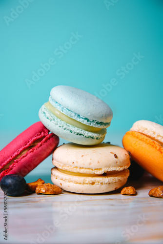 Colorful macarons. Small French cakes. Sweet and colorful french macaroons. Many tasty macarons with fresh berries, raspberries and blueberries, nuts and strawberries on a green background photo