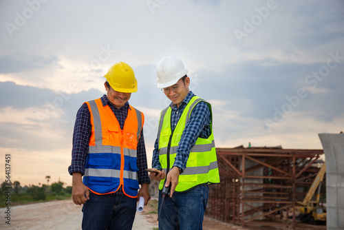 Engineer and foreman worker checking project at building site, Engineer and builders in hardhats discussing blueprint on construction site, Teamwork concepts