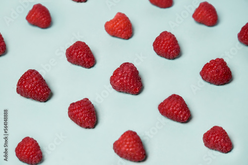 Raspberry pattern on the blue color of the lagoon. Fruits and healthy food, trendy photo.