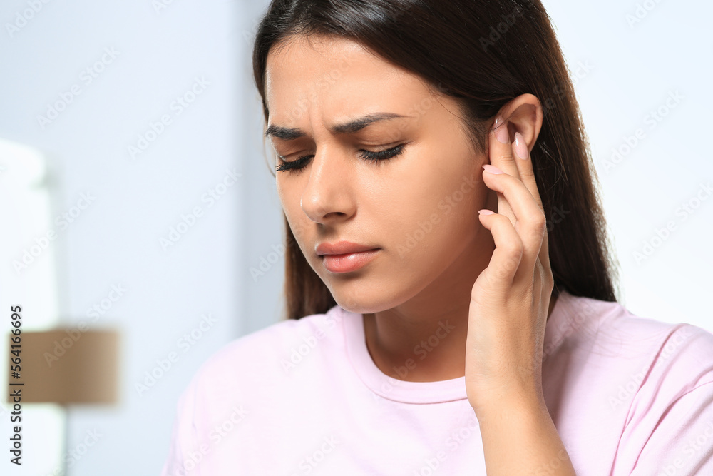Young woman suffering from ear pain indoors, closeup Young woman suffering from ear pain indoors, closeup