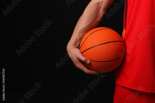 Athletic man with basketball ball on black background, closeup. Space for text © New Africa