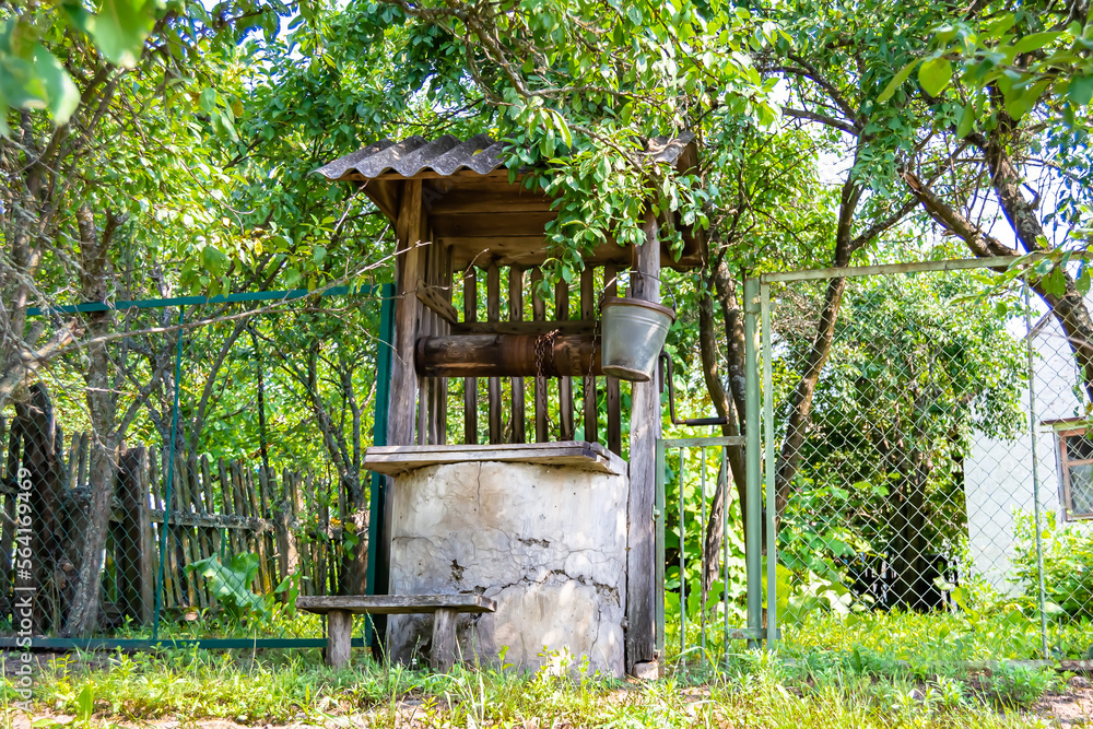 Old well with iron bucket on long forged chain for clean drinking water Old well with iron bucket on long forged chain for clean drinking water