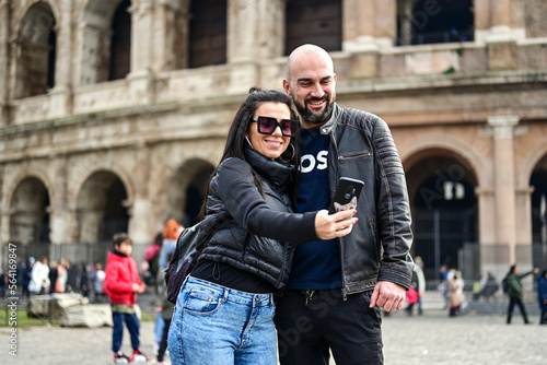 Happy  Beautiful Tourists  couple traveling at Rome, Italy, poses in front of  Colosseum  at, Rome, Italy © Striker777