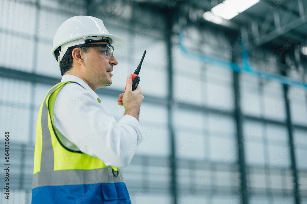 warehouse manager with tablet and radio communication his worker working in background in warehouse distribution center environment. Business warehouse inventory,contruction warehouse warehouse manager with tablet and radio communication his worker working in background in warehouse distribution center environment. Business warehouse inventory,contruction warehouse