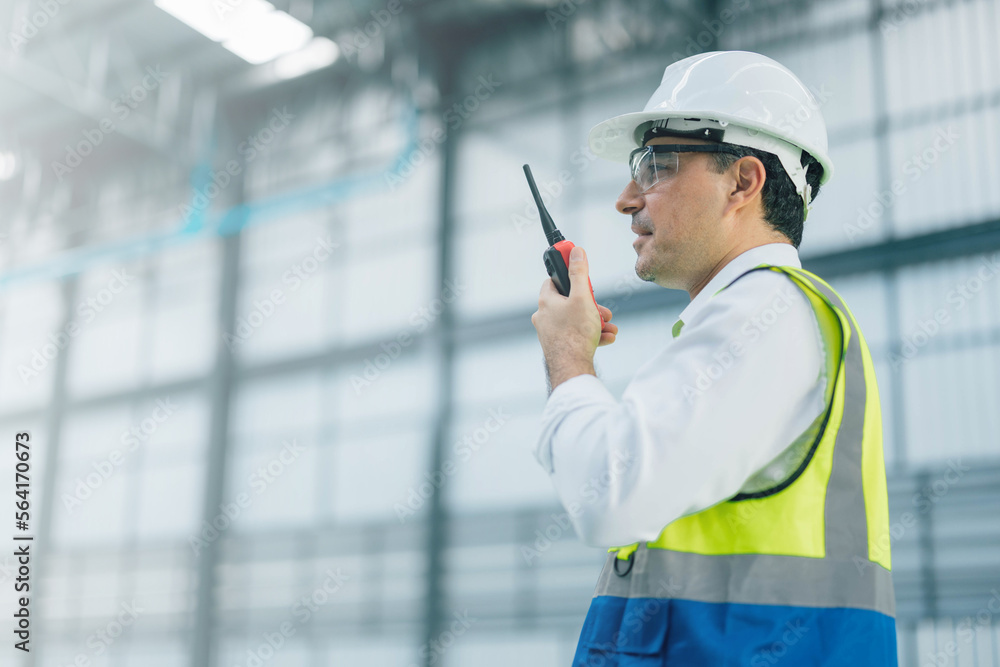 warehouse manager with tablet and radio communication his worker working in background in warehouse distribution center environment. Business warehouse inventory,contruction warehouse warehouse manager with tablet and radio communication his worker working in background in warehouse distribution center environment. Business warehouse inventory,contruction warehouse