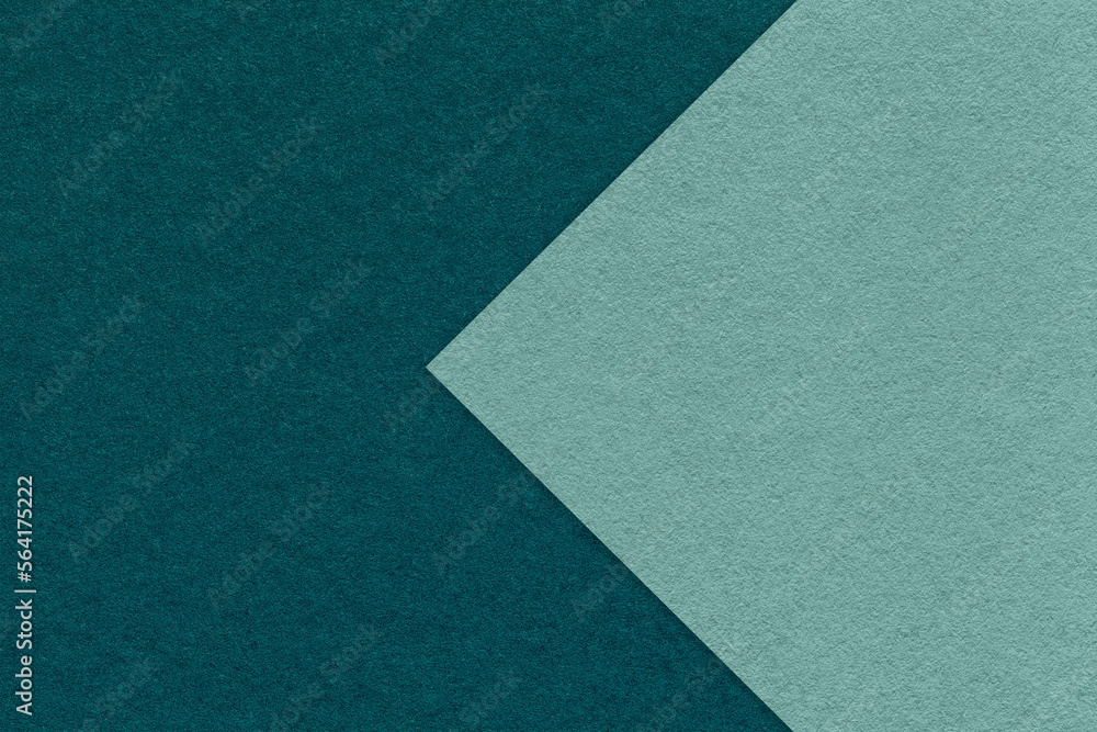 Texture of dark emerald paper background, half two colors with cyan arrow, macro. Structure of craft teal cardboard.