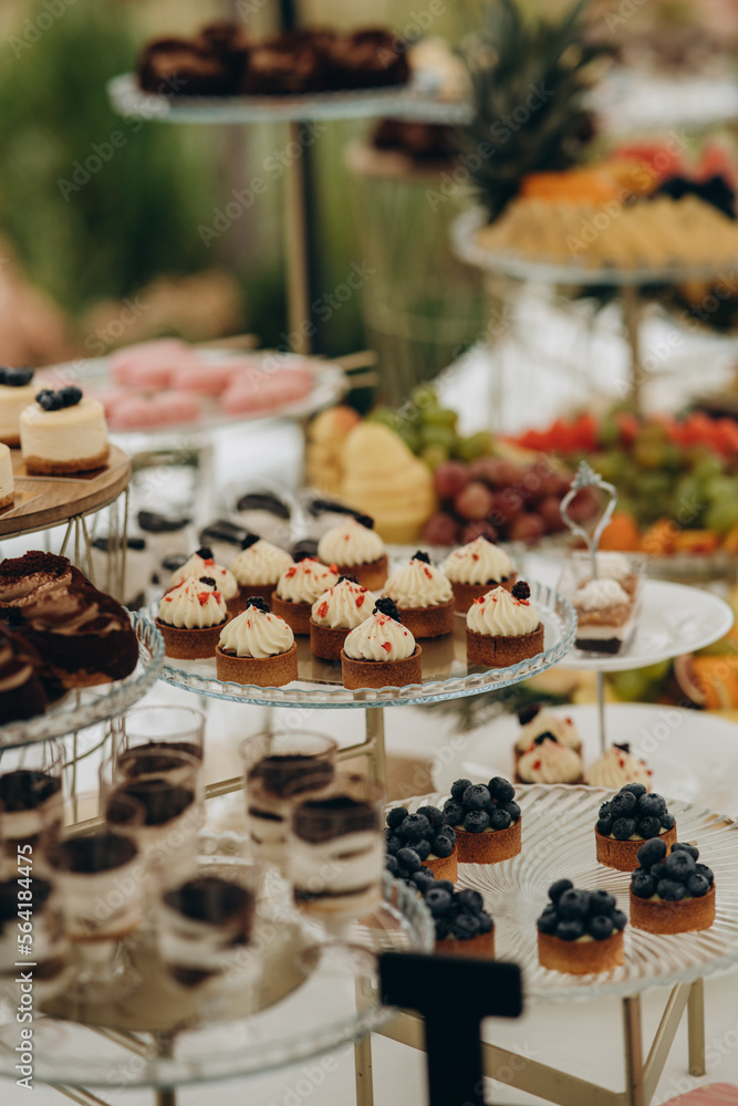 Naklejka premium Dessert table for a party. Ombre cake, cupcakes, sweetness and flowers