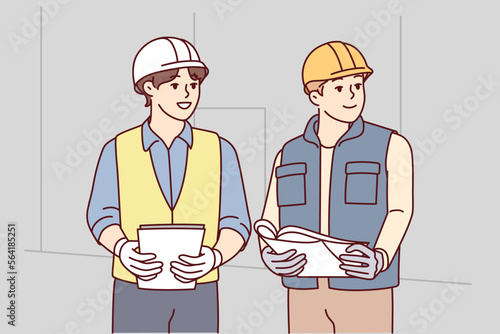 Two man builders in worker uniform look to side discussing construction process. Architects or engineers wearing protective helmets stand with papers in their hands at workplace. Flat vector image