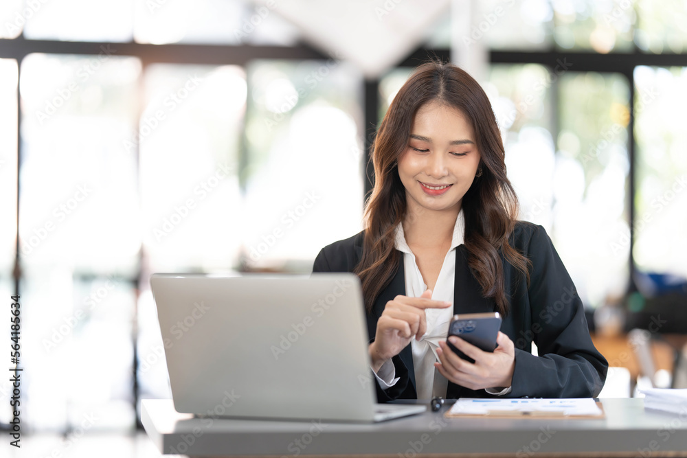Charming Asian woman working at the office using a laptop Looking at the camera. Charming Asian woman working at the office using a laptop Looking at the camera.