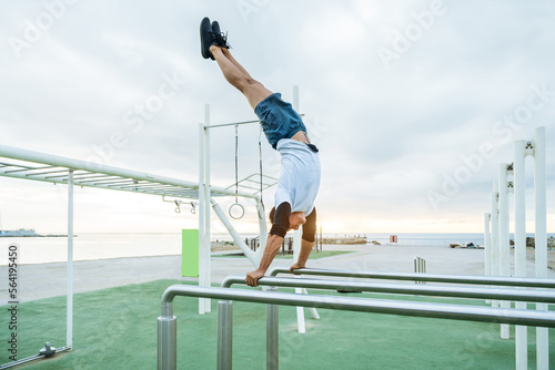 Athletic man doing functional training exercises at the outdoor gym - Sportive adult wearing sportswear training outdoors, workout at gymnastics bar - Sport, healthy lifestyle and fitness concepts