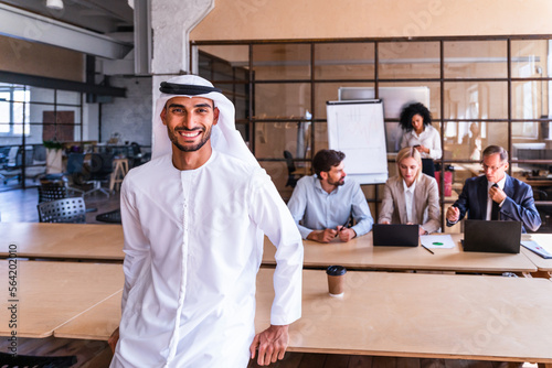 Multiethnic business team meeting in the office, portrait of arab businessman wearing traditional emirates dishdasha working in a corporate business office with his colleagues photo