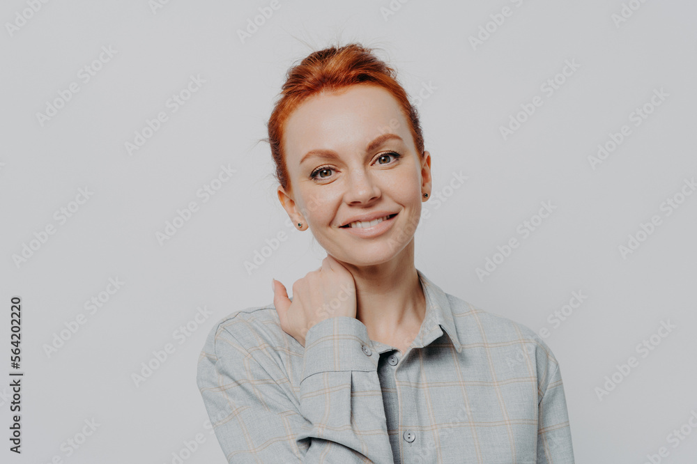 Young attractive smiling female with ginger hair in casual outfit isolated on grey studio background Young attractive smiling female with ginger hair in casual outfit isolated on grey studio background