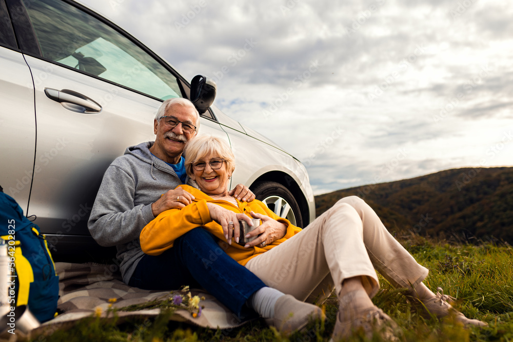 Senior couple sitting against the car, resting after hiking in countryside. Senior couple sitting against the car, resting after hiking in countryside.