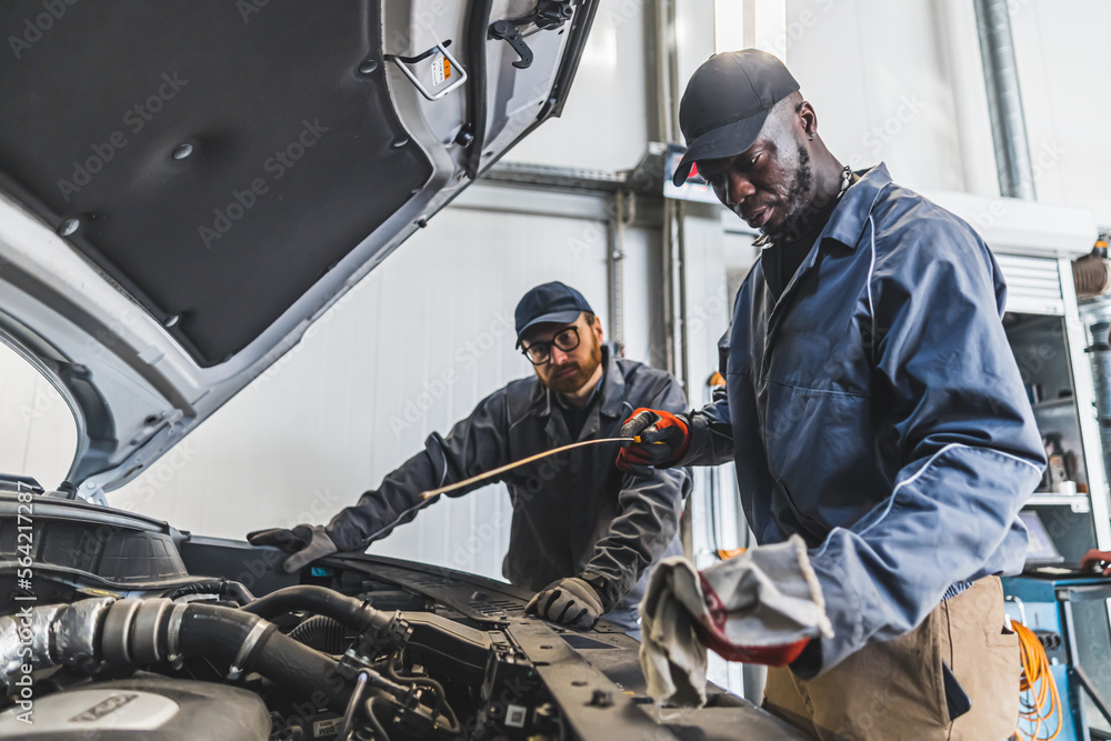 Skilled mechanics repairing a car engine using tools in a modern auto repair shop. High-quality photo