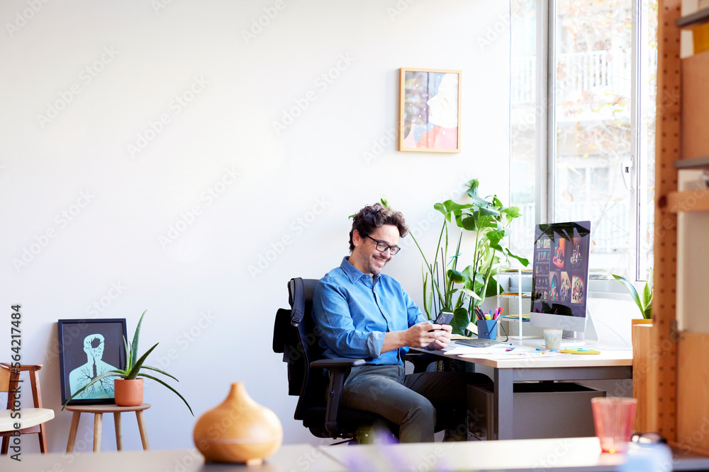 Smiling man using smartphone in office Smiling man using smartphone in office