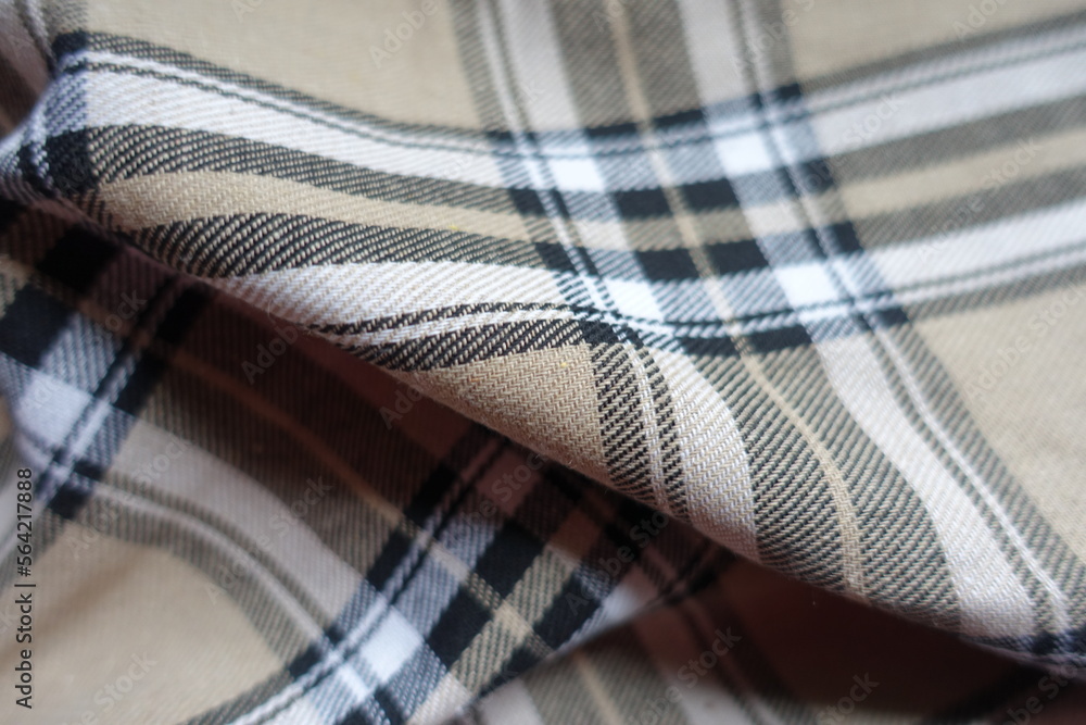 Diagonal soft fold on beige, black and white cotton flannel tartan fabric Diagonal soft fold on beige, black and white cotton flannel tartan fabric