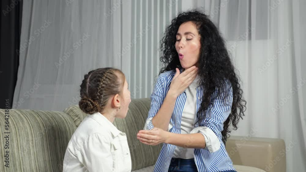 Female speech therapist helps girl kid to make correct sound and teaches child to words right. Junior schoolgirl learns to pronounce sounds at home Female speech therapist helps girl kid to make correct sound and teaches child to words right. Junior schoolgirl learns to pronounce sounds at home