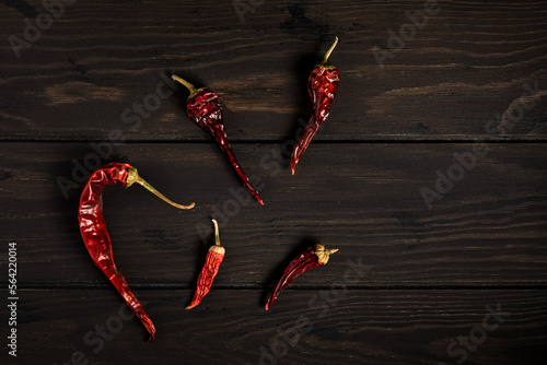 Dried red chili peppers on dark wooden background, copy space, top view