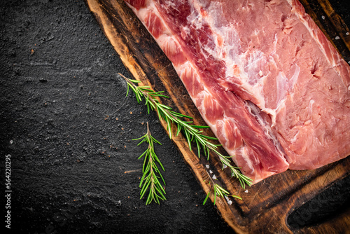 Fresh raw pork on a cutting board with rosemary.